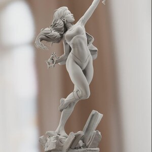 K&ouml;nnte beinhalten: Graue Skulptur einer Frau in dynamischer Pose, mit einem Arm erhoben und dem anderen eine Ansammlung von Objekten haltend. Die Figur steht auf einem felsigen Sockel. Die Skulptur hat langes, flie&szlig;endes Haar und tr&auml;gt ein figurbetontes Outfit.