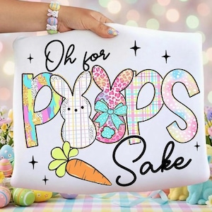 May include: White pillow with the text "Oh for Peeps Sake" and Easter-themed graphics. The design includes two bunny figures, a carrot, and star accents. The bunnies have colorful patterns and a bow.