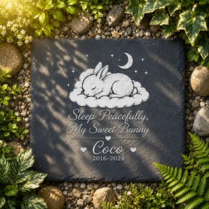 Może przedstawiać: Ciemnoszara kamienna tablica pamiątkowa z ilustracją śpiącego kr&oacute;lika, księżycem i gwiazdami. Tekst brzmi "Sleep Peacefully, My Sweet Bunny Coco 2016-2024". Tablica otoczona jest zielenią i małymi kamieniami.