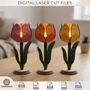 May include: Three laser-cut tulip lamps in pink, orange, and yellow, each with a warm LED light. The lamps have green stems and leaves, and are set on a wooden table. The text "DIGITAL LASER CUT FILES" is at the top. The lamps are made from wood.