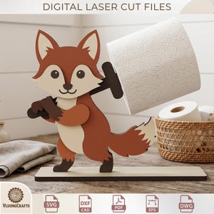 May include: A wooden fox-shaped toilet paper holder. The fox is brown, cream, and black, holding a roll of white toilet paper. The base is a light brown rectangle. The text "DIGITAL LASER CUT FILES" is at the top.