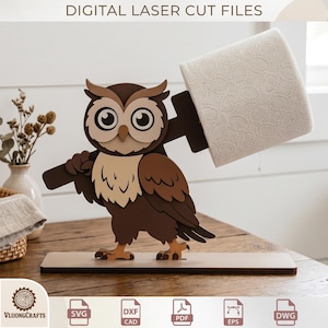 May include: A wooden owl-shaped toilet paper holder. The owl is brown, beige, and white, holding a brown arm that supports a roll of white toilet paper. The base is a light brown rectangle. The text "DIGITAL LASER CUT FILES" is at the top.