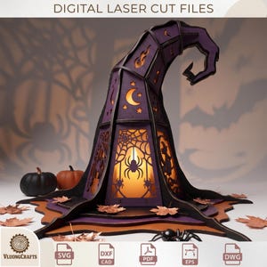 May include: A purple and black laser-cut wooden witch hat lantern featuring cutouts of spiders, webs, moons, stars, and a witch silhouette. The structure is illuminated from within, casting shadows. Text at the top reads DIGITAL LASER CUT FILES.