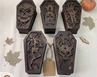 May include: Five dark brown wooden coffin-shaped boxes with intricate laser-cut designs including a skull, a cat on a tombstone, a skeletal hand, a full skeleton with chains, and a horned skull. The text DIGITAL LASER CUT FILES is at the top.
