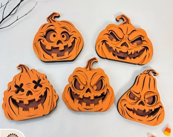 May include: Five layered orange wooden pumpkin decorations with various carved facial expressions including wide grins, jagged teeth, and X-shaped eyes. The text DIGITAL LASER CUT FILES is at the top, and file format icons SVG, DXF, PDF, EPS, and DWG are at the bottom.