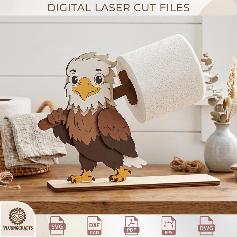 May include: A laser-cut wooden eagle toilet paper holder. The eagle, with brown, tan, and white details, holds a roll of white toilet paper. The base is a light brown rectangle. The text "DIGITAL LASER CUT FILES" is at the top.