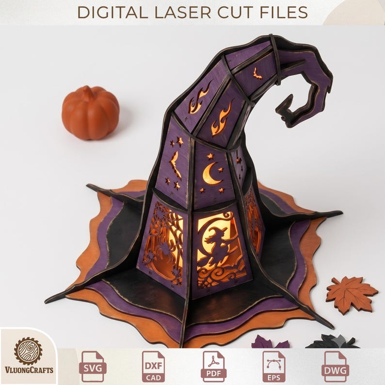 May include: A purple and black laser-cut wooden witch hat decoration featuring cutouts of a witch on a broom, crescent moons, stars, bats, and flames. The structure is illuminated from within and accompanied by a small orange pumpkin and leaf.