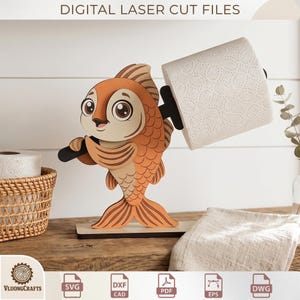 May include: A wooden fish-shaped toilet paper holder. The fish is orange and tan with large eyes and holds a black bar supporting a roll of white toilet paper. The base is a light brown rectangle. The text "DIGITAL LASER CUT FILES" is at the top.