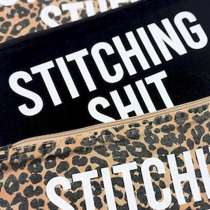 Könnte beinhalten: Nahaufnahme von drei Reißverschlusstaschen mit dem Text "STITCHING SHIT" in fetten weißen Buchstaben. Eine Tasche ist schwarz, und zwei haben ein braunes und schwarzes Leopardenmuster. Die Taschen sind wahrscheinlich für die Aufbewahrung von Nähutensilien.
