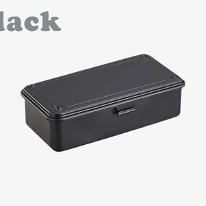 May include: A black rectangular toolbox with a handle and a hinged lid. The word "black" is printed in gray above the toolbox. The toolbox has a matte finish and is likely made of metal.