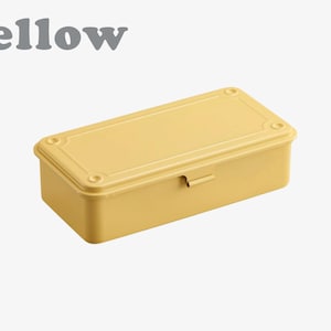 May include: A yellow rectangular box with a lid, featuring rounded corners and a small latch. The word "yellow" is printed in gray above the box. The box is a solid, pale yellow color.
