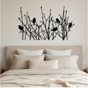 May include: A black metal wall art piece featuring a silhouette design of four birds perched on thin, leafless branches. The artwork displays a horizontal arrangement of vertical twigs and stems with small buds, creating a nature-inspired pattern.