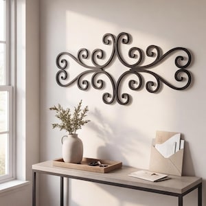 May include: A dark brown metal wall art piece featuring a symmetrical scrollwork design with multiple interconnected swirls and curves. The decorative object is mounted horizontally on a plain wall, showcasing a continuous, fluid, and ornate pattern.