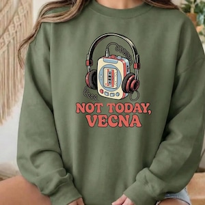 May include: An olive green sweatshirt featuring a retro-style graphic of a cassette player with headphones. The text "NOT TODAY, VECNA" is printed in red, adding a pop of color to the design. The sweatshirt has long sleeves and a crew neck.