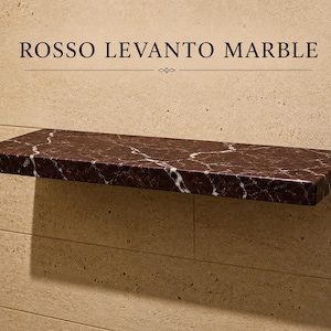 Pu&ograve; includere: Una mensola rettangolare sospesa in marmo rosso scuro Rosso Levanto con venature bianche prominenti. La mensola &egrave; montata orizzontalmente su una parete in pietra beige chiaro. Il testo ROSSO LEVANTO MARBLE &egrave; stampato sopra la mensola.