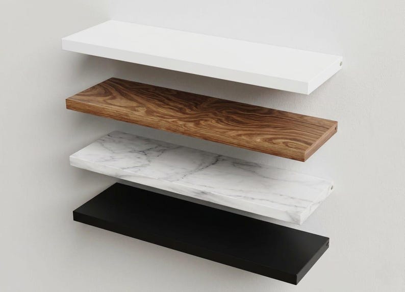 Pu&ograve; includere: Una pila di quattro mensole rettangolari sospese montate orizzontalmente. La mensola superiore &egrave; bianco tinta unita, la seconda presenta una venatura del legno marrone, la terza ha una texture in marmo bianco e grigio e la mensola inferiore &egrave; nero opaco.