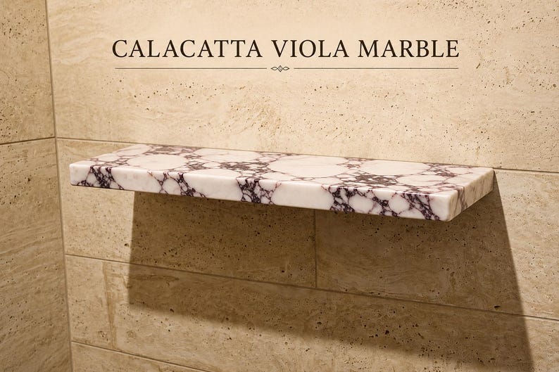 Pu&ograve; includere: Una mensola rettangolare da parete in marmo Calacatta Viola, caratterizzata da una base bianca con venature viola scuro. Il testo CALACATTA VIOLA MARBLE &egrave; stampato sopra la mensola, fissata su una parete con piastrelle beige.