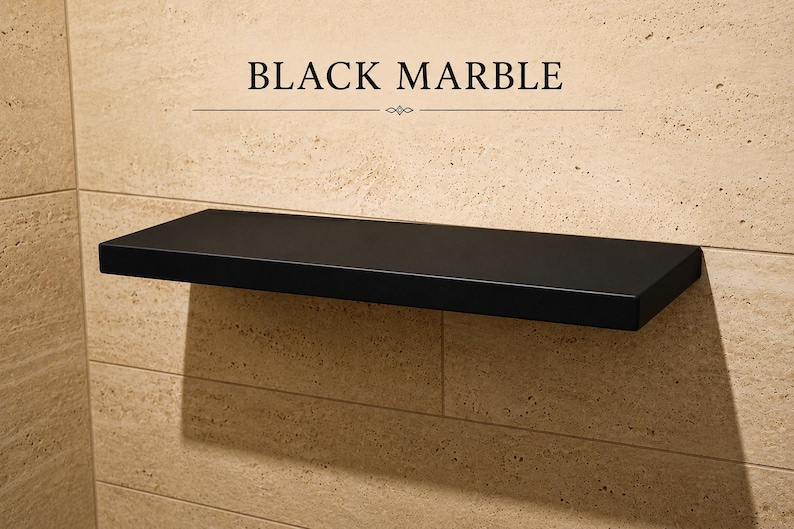 Pu&ograve; includere: Una mensola rettangolare sospesa in marmo nero montata su una parete piastrellata color beige. Il testo "BLACK MARBLE" &egrave; stampato in nero sopra la mensola, accompagnato da una linea orizzontale decorativa con un piccolo emblema centrato.