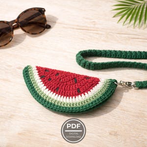 Könnte beinhalten: Gehäkelte wassermelonenförmige Tasche mit grünem Riemen und silbernem Verschluss. Die Tasche hat rote, weiße und grüne Garne mit schwarzen Kerndetails. Sonnenbrille liegt auf einer hellen Holzoberfläche. Das Bild enthält ein Symbol für digitalen Download.