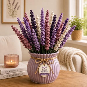 Puede incluir: Un ramo de flores de lavanda de ganchillo en tonos morados, rosas y blancos, dispuesto en un jarrón acanalado de color lila claro. El jarrón está atado con hilo y una etiqueta que dice "PDF Digital Download US Term". Una vela en un portavelas de cristal rosa.