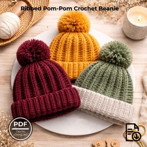 May include: Three ribbed pom-pom crochet beanies in burgundy, mustard yellow, and olive green with cream-coloured brim. The beanies are displayed on a white plate. The text "Ribbed Pom-Pom Crochet Beanie" is at the top of the image.
