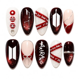 Può includere: Un set di dieci unghie finte a mandorla con finitura glitter rosso scuro, accenti glitter bianchi e basi color crema. I design includono il logo BTS, il numero 7, motivi a costellazione, nastri rossi e testo con i nomi dei membri.