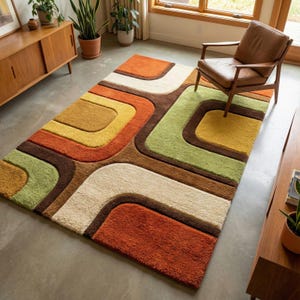 May include: A rectangular area rug featuring a geometric pattern of rounded, interlocking shapes in shades of burnt orange, mustard yellow, sage green, cream, and dark brown. The rug has a thick, textured pile and a soft, plush appearance.