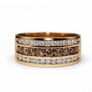 Könnte beinhalten: Ein goldener Bandring mit drei Reihen von Edelsteinen. Die oberen und unteren Reihen weisen klare, weiße Edelsteine auf, während die mittlere Reihe braune Edelsteine aufweist. Der Ring ist vor einem weißen Hintergrund platziert.