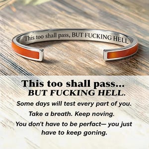May include: A silver-toned metal cuff bracelet featuring an orange inlay and the engraved text "This too shall pass, BUT FUCKING HELL" on the inner surface. The bracelet has an open design and a polished finish, displaying the text clearly.