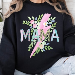 Peut inclure: Sweat-shirt noir avec le mot "MAMA" dans un motif floral et léopard, orné d'un éclair rose et d'éléments floraux. Un haut décontracté.