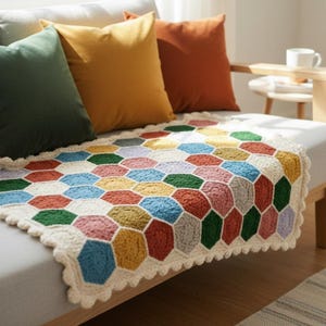 Puede incluir: Una colorida manta de ganchillo hecha a mano con un patrón de panal en varios colores, incluyendo rojo, azul, amarillo y verde. La manta está colocada sobre un sofá gris con cojines naranjas, amarillos y verdes. La manta mide aproximadamente 100 cm x 150 cm.