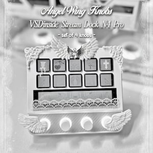 May include: A white VSDinside Stream Dock N4 Pro featuring four circular knobs adorned with sculpted angel wings. The device includes a top-mounted angel wing emblem with a central heart, a lace trim accent, and ten square display buttons.