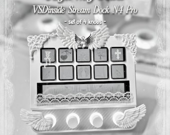 Puede incluir: Un VSDinside Stream Dock N4 Pro blanco con cuatro perillas circulares adornadas con alas de ángel esculpidas. El dispositivo incluye un emblema de alas de ángel en la parte superior con un corazón central, un borde de encaje y diez botones.
