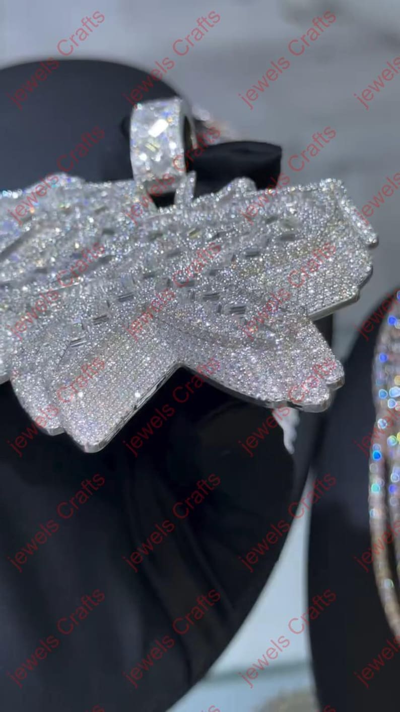 May include: Close-up of a silver pendant and ring set with numerous small, sparkling crystals. The pendant has a unique, layered design. The ring features a large, square-cut crystal. The jewelry is set against a dark background.