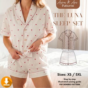 Op de afbeelding: Witte pyjamaset met rood hartjespatroon. De set bevat een overhemd met korte mouwen en bijpassende shorts. De randen zijn afgewerkt met rode biezen. De tekst op de afbeelding luidt "THE LUNA SLEEP SET" en "Maten: XS / 5XL".