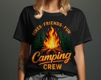 May include: Black t-shirt with a camping theme. The design features a campfire with flames, logs, and green trees. The words "Fires, Friends, Fun" and "Camping Crew" are in orange.