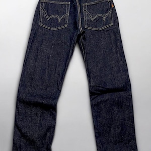 K&ouml;nnte beinhalten: Dunkelblaue Jeans mit gelben N&auml;hten. Die R&uuml;ckseite der Jeans hat zwei Taschen mit einem einzigartigen geschwungenen Design. Ein braunes Lederetikett mit dem Markennamen ist am Bund sichtbar. Die Jeans haben eine klassische, gerade Passform.