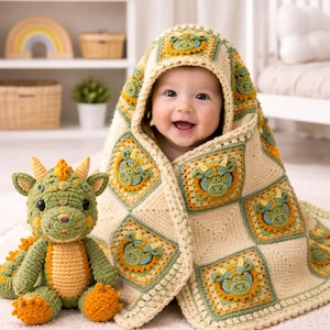 Può includere: Un bambino sorridente avvolto in una coperta all'uncinetto con cappuccio color crema con motivi di draghi verdi e gialli. Un giocattolo a forma di drago all'uncinetto verde e arancione abbinato è nelle vicinanze. La coperta e il giocattolo sono fatti a mano.