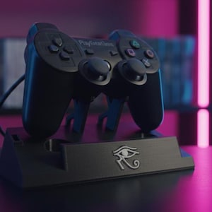 May include: A black video game controller resting on a black charging stand. The stand features a silver eye symbol. The controller has multiple buttons and analog sticks. The background includes a bookshelf and neon lighting.