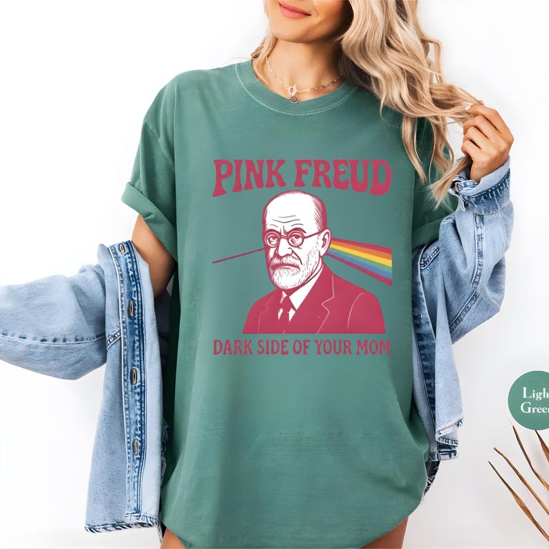 May include: Light green t-shirt with the text "PINK FREUD" above an illustration of Sigmund Freud with a rainbow beam and the text "DARK SIDE OF YOUR MOM" below.