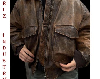 May include: Brown leather jacket with a distressed finish, featuring a zip-up front, two front pockets, and a black collar. The jacket has the text "ARIZ INDUSTRY" printed on the left side.