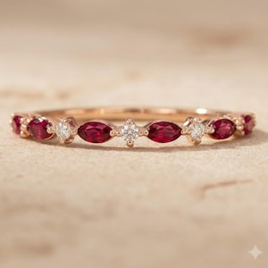 Peut inclure: Une bague en or rose ornée d'un motif alterné de rubis rouge foncé taille marquise et de petits diamants blancs taille brillant ronde, disposés sur la moitié supérieure de l'anneau en métal de manière délicate et symétrique.