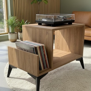 May include: A wooden record player stand with a black turntable and a collection of vinyl records. The stand has a light brown wood grain finish, black legs, and a shelf for record storage. The turntable is black with a clear cover.