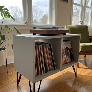 Small-space wooden vinyl stand pairing a turntable surface with compact LP storage in a minimalist form.