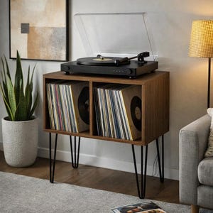 May include: A dark wood record player stand with two open storage compartments filled with vinyl records. A black turntable with a clear plastic dust cover sits on top. The stand features four thin black metal hairpin legs.