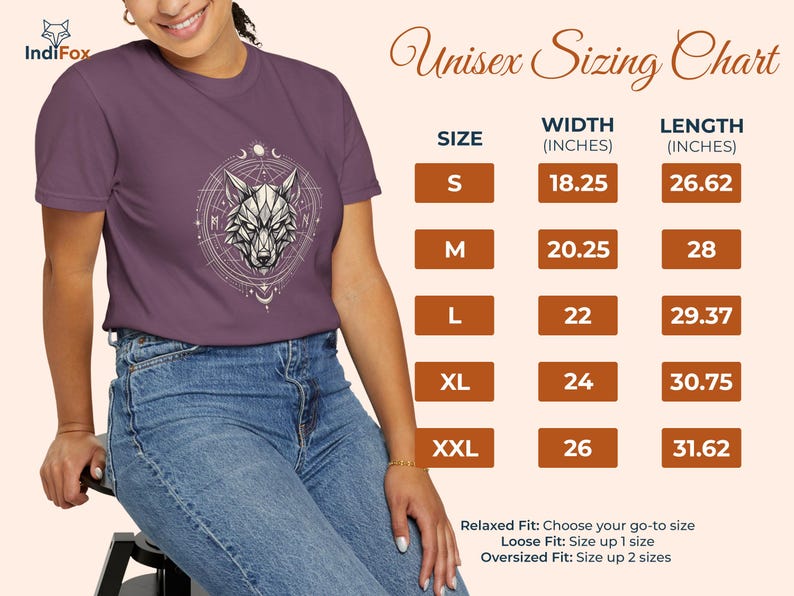 Pu&ograve; includere: Una maglietta viola con un disegno geometrico di una testa di lupo all'interno di un cerchio. L'immagine include una tabella delle taglie con misure in centimetri e il testo "Unisex Sizing Chart". La modella indossa jeans blu.