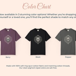 Pu&ograve; includere: Tabella dei colori con tre magliette nei colori bacca, nero e pepe. Ogni maglietta presenta una grafica dettagliata di un lupo. Il testo recita "Ora disponibile in 3 splendide opzioni di colore!" e "Realizzato con tessuto di cotone ring-spun morbido al 100%."