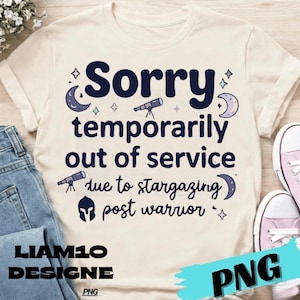 May include: Cream-colored t-shirt with the text "Sorry temporarily out of service due to stargazing post warrior." The design includes illustrations of moons, stars, and telescopes. The brand name "LIAM10 DESIGNE" is printed at the bottom.