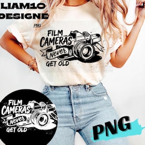 Op de afbeelding: Crèmekleurig T-shirt met een zwart-witte afbeelding van een filmcamera en de tekst "FILM CAMERAS Never GET OLD". Het ontwerp bevat een lintbanner en is een PNG-bestand.