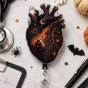 May include: A badge reel featuring a heart-shaped design with a dark Halloween-themed illustration of a haunted house, ghost, and pumpkins. Attached is a clear plastic ID holder with a white card labeled RN Registered Nurse and a barcode.